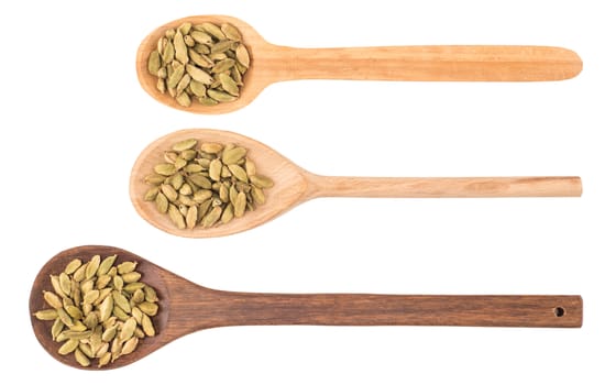 Cardamom seeds in the wooden spoon on white background