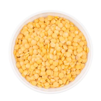 Bowl of yellow split lentil isolated on white background, top view