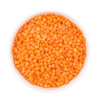 Bowl of red split lentil isolated on white background, top view