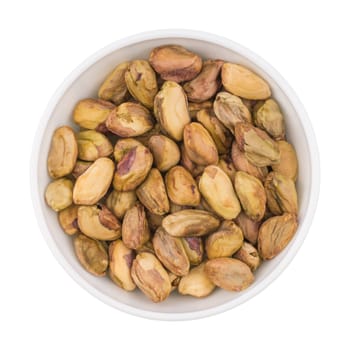 At the center of the frame white bowl with raw pistachio kernels on a white background. Raw pistachio kernels. Close. Horizontal shot. Top view.