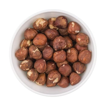 White ceramic cup bowl filled with the multiple hazelnuts isolated over the white background