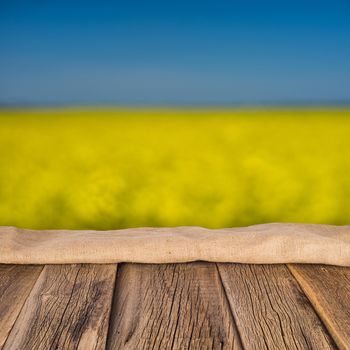 empty wooden planks with blurred background blooming yellow rape flowers