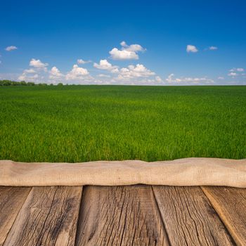 Wooden deck table over beautiful meadow with blue sky