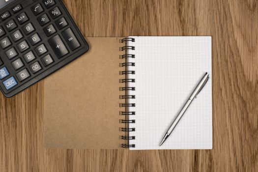 Notebook, ballpen and calculator on wooden desk