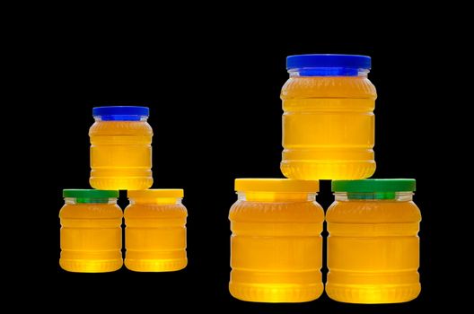 Jars of honey with colorful caps isolated on black background