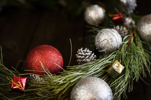 Christmas wreath of fir branches with Christmas decorations, pine cones and gifts on the brown background