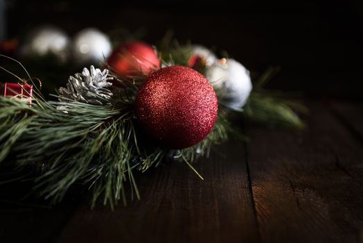 Christmas wreath of fir branches with Christmas decorations, pine cones and gifts on the brown background