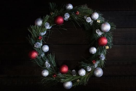 Christmas wreath of fir branches with Christmas decorations, pine cones and gifts on the brown background