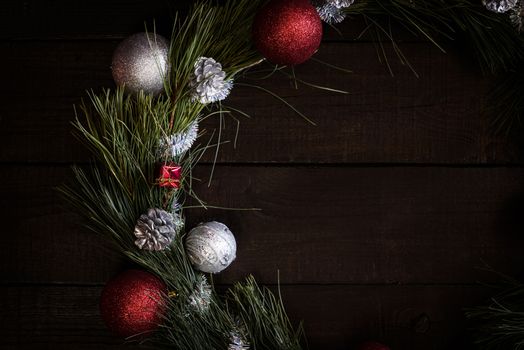 Christmas wreath of fir branches with Christmas decorations, pine cones and gifts on the brown background