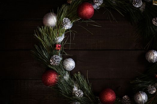 Christmas wreath of fir branches with Christmas decorations, pine cones and gifts on the brown background