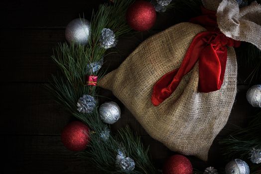 Christmas wreath of fir branches with Christmas decorations, pine cones and gifts on the brown background