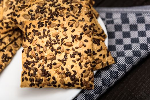 cookies with sunflower seeds and sesame seeds on a white plate with checkered napkin