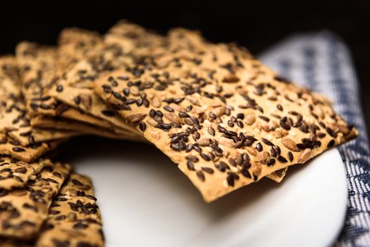 cookies with sunflower seeds and sesame seeds on a white plate with checkered napkin