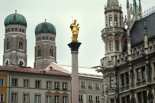 The Golden statue of Mary (Mariensaule), a Marian column on the Marienplatz, Frauenkirche in the background in Munich, German