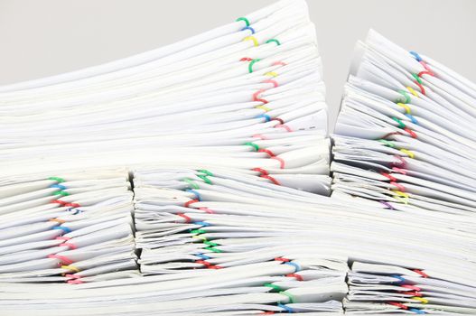 Close up pile overload report and receipt with colorful paperclip place on white background.