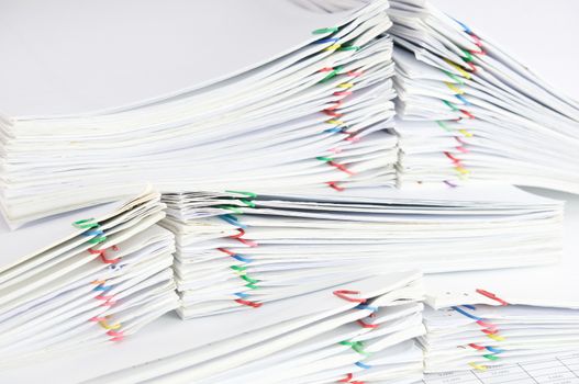 Close up pile overload report and receipt with colorful paperclip.