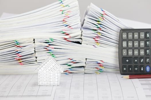 House on finance account have blur brown pencil with calculator place vertical and pile overload paperwork of report and receipt with colorful paperclip place on white background.