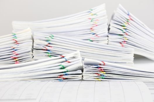 Pile overload report and receipt with colorful paperclip place on finance account with white background.
