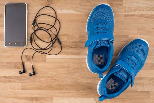 Flat lay shot of Sport equipment. Sneakers, earphones and phone on wooden background. 