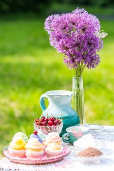 cupcakes, cherry and jug on the table in the garden