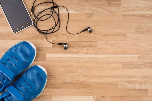 Flat lay shot of Sport equipment. Sneakers, earphones and phone on wooden background. 