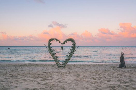 Palm tree branches are tied into the shape of a heart, on a quiet beach on the island of Koh Pha Ngan, Thailand .