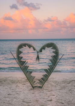 Palm tree branches are tied into the shape of a heart, on a quiet beach on the island of Koh Pha Ngan, Thailand .