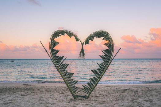 Palm tree branches are tied into the shape of a heart, on a quiet beach on the island of Koh Pha Ngan, Thailand .