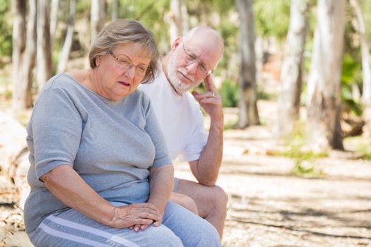 Very Upset Senior Woman Sits With Concerned Husband Outdoors.