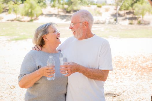 Happy Healthy Senior Couple with Water Bottles Outdoors.