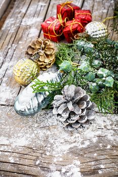 Pine and pinecone Christmas decorations on snowy wooden background