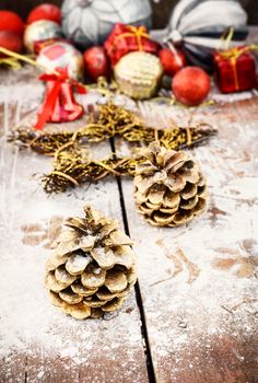 Pine and pinecone Christmas decorations on snowy wooden background
