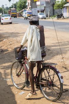 Documentary editorial image. Pondicherry, Tamil Nadu, India - June 05 2014. Very poor old man cycling in the street, hungry, bad nutrition. Poverty