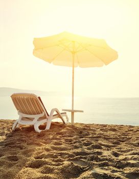 Beach loungers on deserted coast sea at sunrise