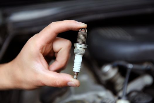 Auto mechanic holds an old spark plug