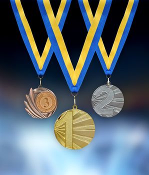 Gold, silver and bronze medals in the foreground with yellow blue ribbon