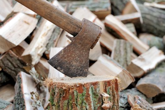 Ax in a log on the background of firewood