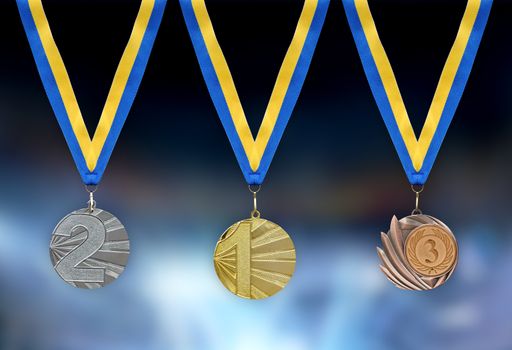 Gold, silver and bronze medals in the foreground with yellow blue ribbon