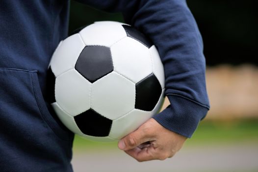 Hand holding soccer ball on stadium