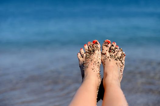  Women's beautiful legs on the beach near sea
