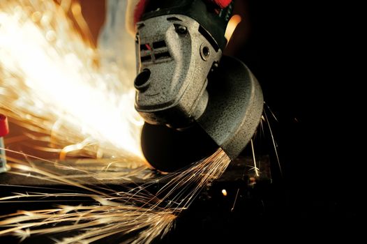 Worker cutting metal with grinder. Sparks while grinding iron