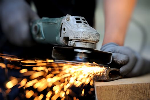 Worker cutting metal with grinder. Sparks while grinding iron