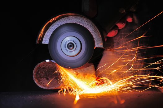 Worker cutting metal with grinder. Sparks while grinding iron