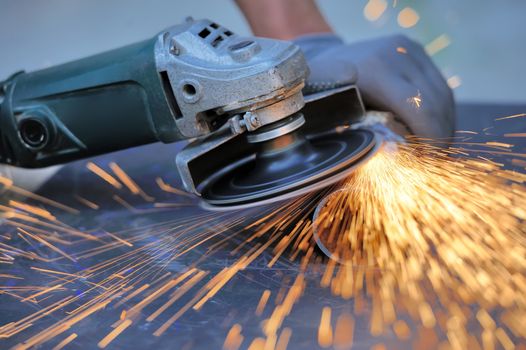 Worker cutting metal with grinder. Sparks while grinding iron