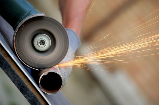 Worker cutting metal with grinder. Sparks while grinding iron