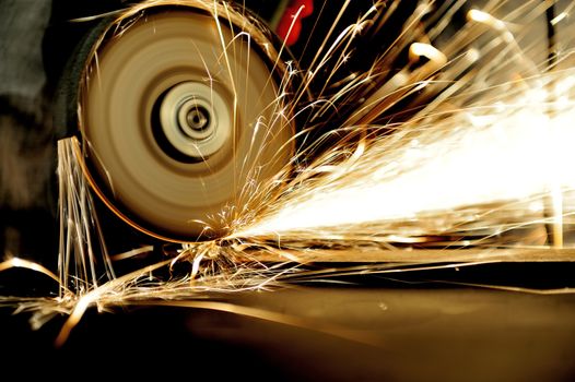 Worker cutting metal with grinder. Sparks while grinding iron