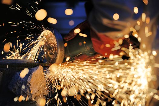 Worker cutting metal with grinder. Sparks while grinding iron