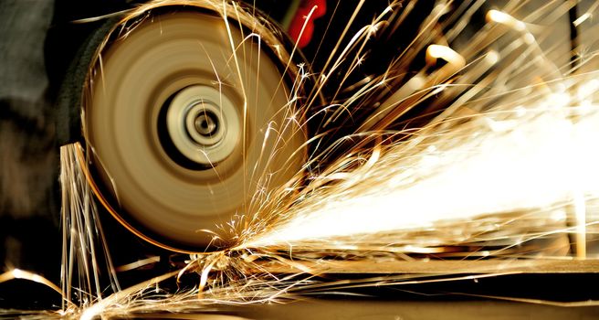 Worker cutting metal with grinder. Sparks while grinding iron