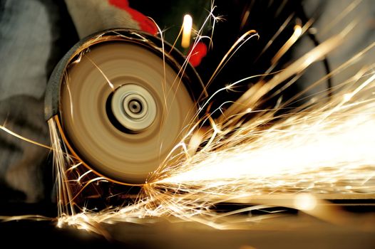 Worker cutting metal with grinder. Sparks while grinding iron