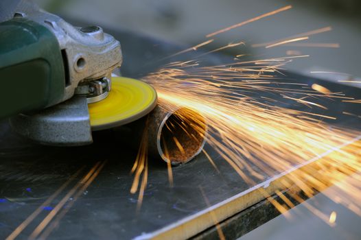 Worker cutting metal with grinder. Sparks while grinding iron